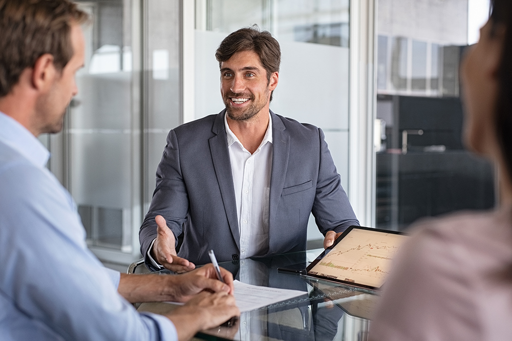 Financial advisor consulting Confident financial agent showing growth graph to couple. Mid couple meeting financial advisor for investment. Business people discussing the charts and graphs showing the results of their successful teamwork.
